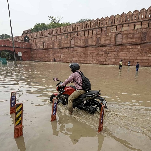 A motorcyclist wades through a flooded road