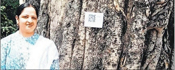 Teacher Nitika Jacob with a tree tagged with a QR code on the school campus