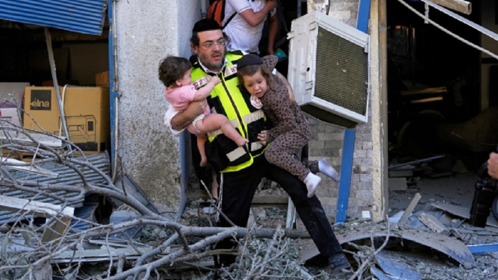 A rescue worker evacuates two children from the site