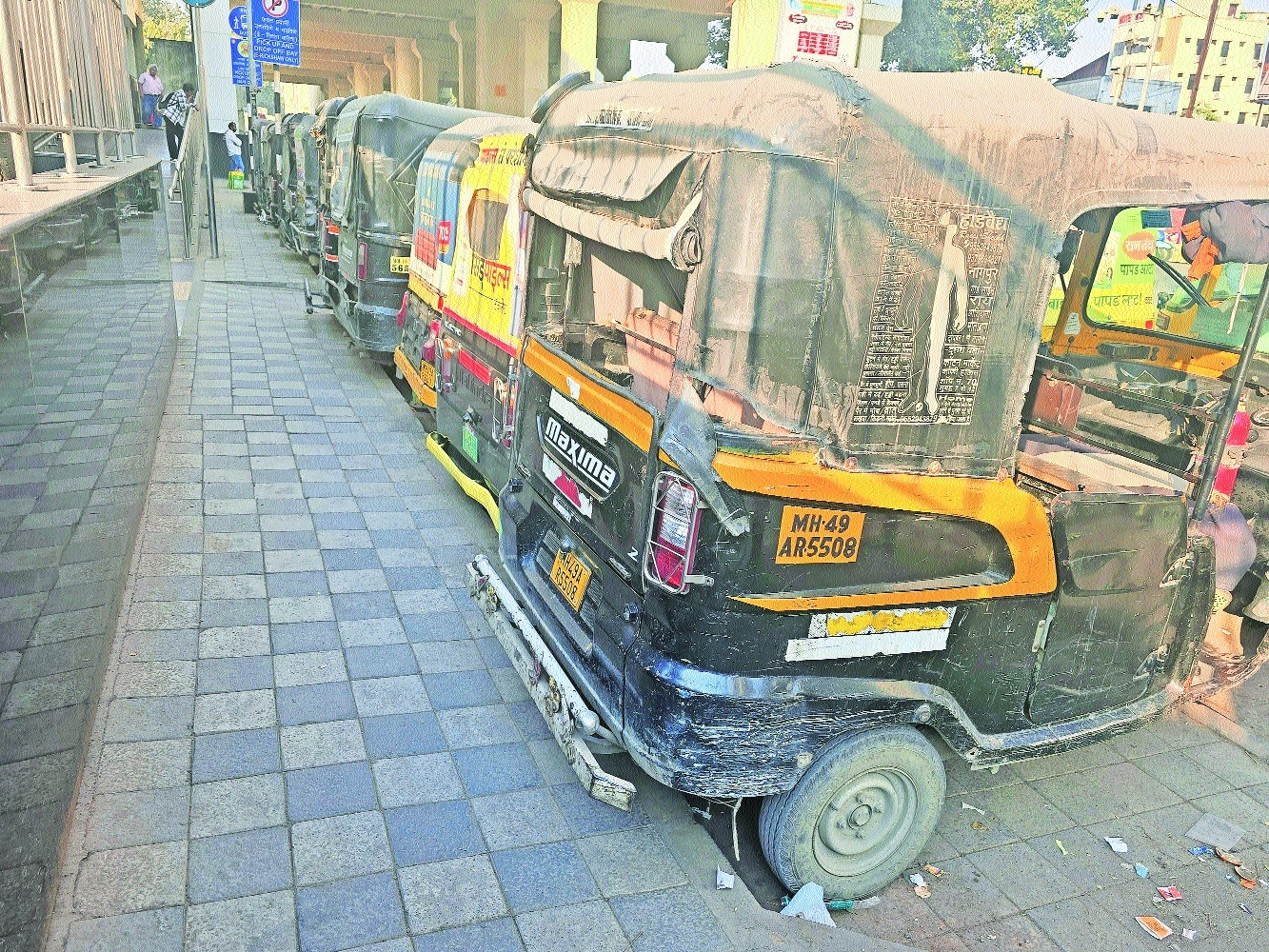 A continuous line of parked autos occupies the entire pedestrian footpath outside Nagpur Railway Station Metro Station